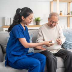 aide assisting the senior man on his medication