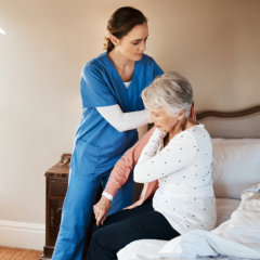 aide helping the senior woman on her cloth