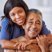 aide hugging senior man and smiling together