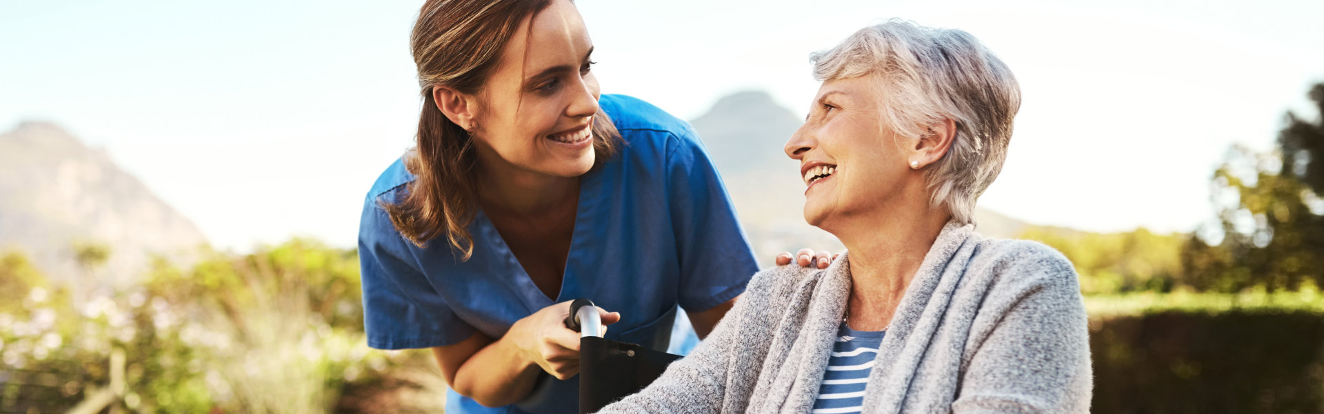 aide and senior woman looking at each other and smiling together
