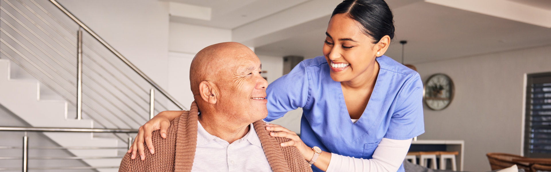 aide and senior man looking at each other and smiling
