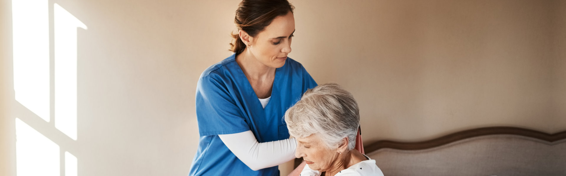 aide helping the senior woman on her cloth